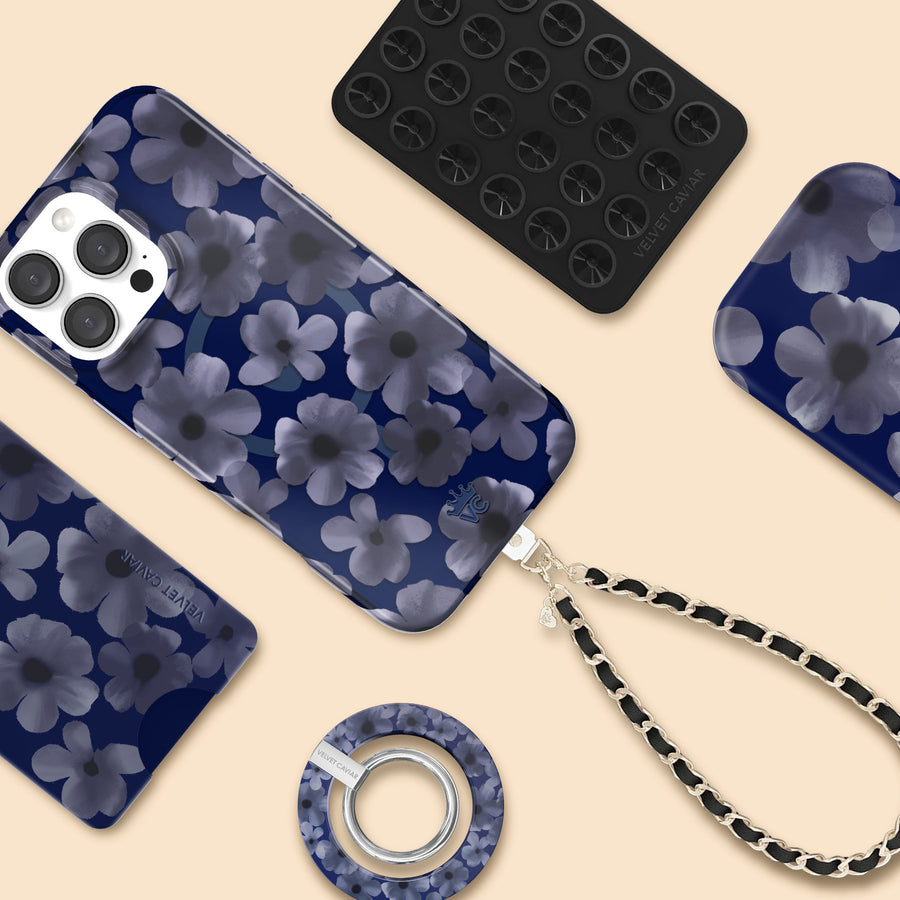 Blue floral phone case collection with matching MagSafe accessories including wireless charger, grip ring, and chain strap on beige background